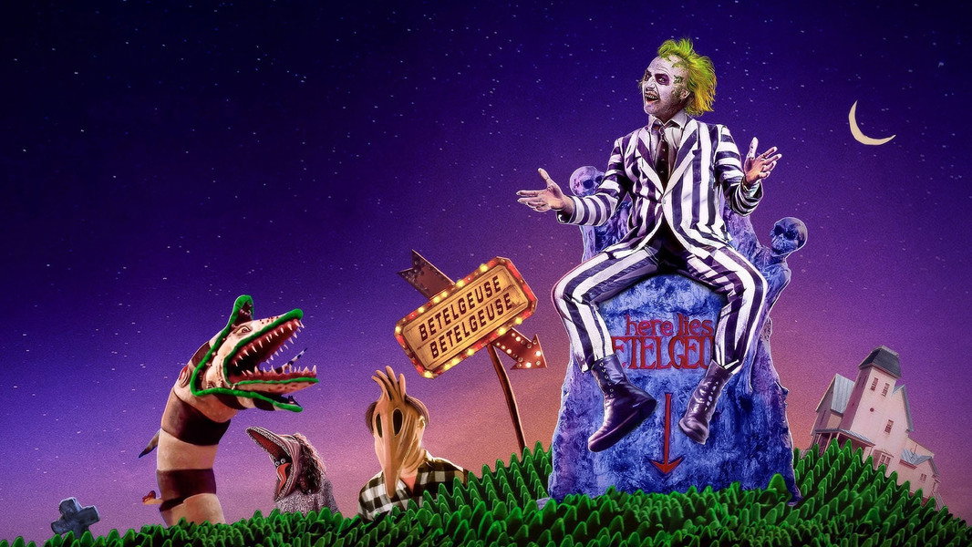 A whimsical scene featuring a character in a striped suit with green hair sitting on a gravestone that reads 'here lies Betelgeuse'. The background shows a starry night sky, with playful elements like a dinosaur head and spooky hands reaching out.